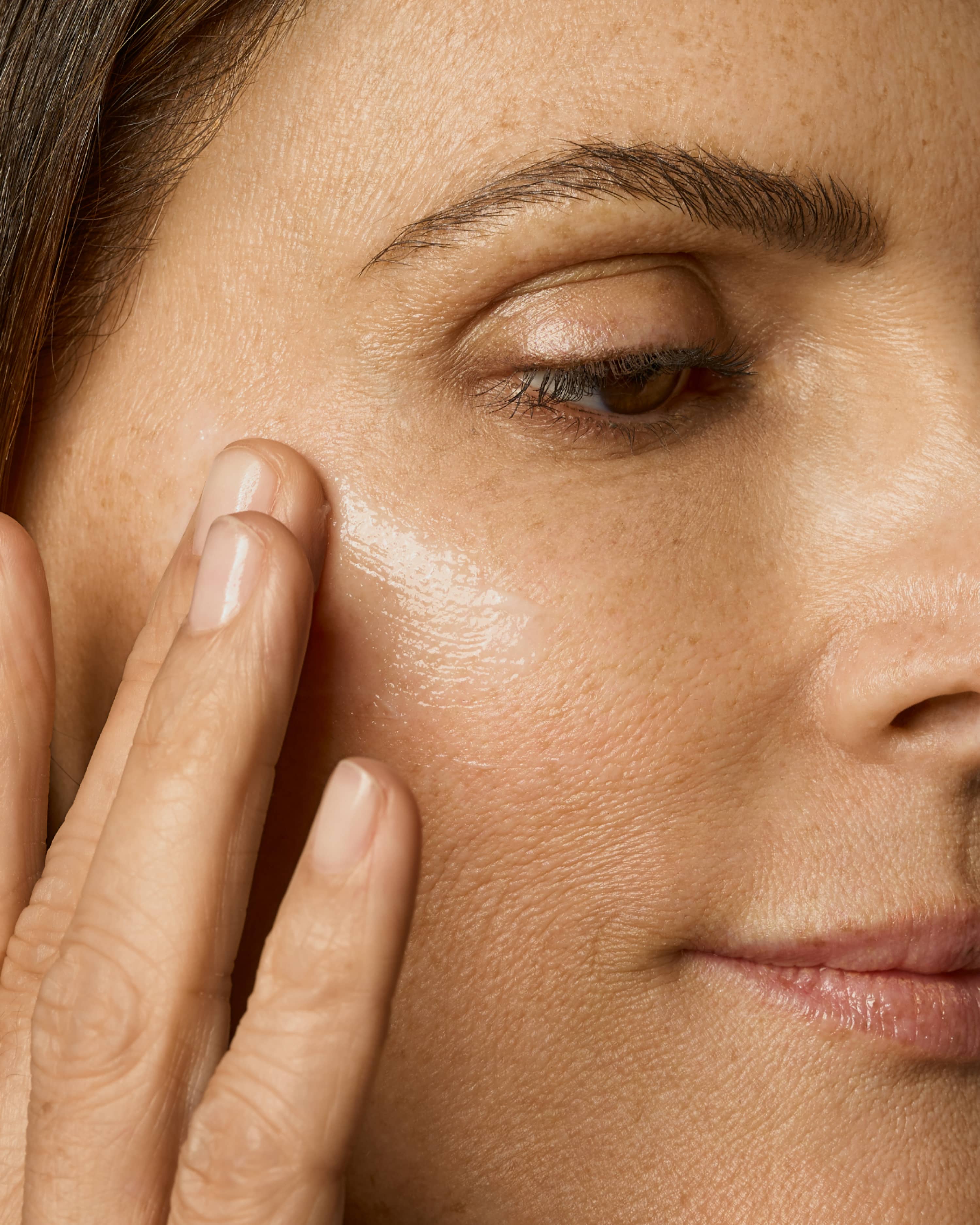 Woman applying glow lotion on cheek