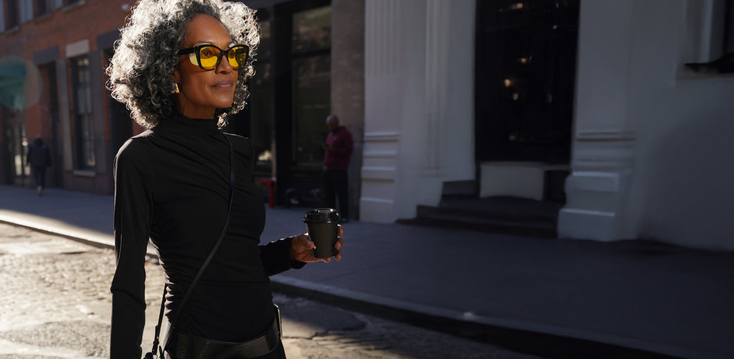 African american woman walking with a coffee, wearing eye patches