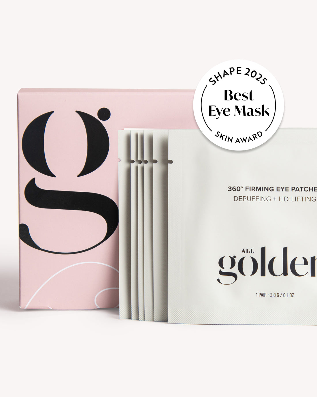 Shape All Golden eye mask sachets and packaging on a clean white background, featuring a pink box with a large black logo and a stack of white individual packets with a &