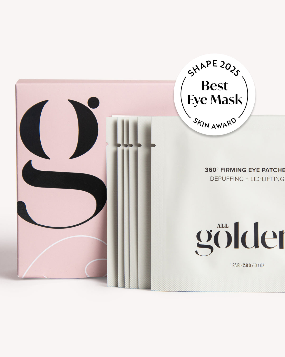 Shape All Golden eye mask sachets and packaging on a clean white background, featuring a pink box with a large black logo and a stack of white individual packets with a &